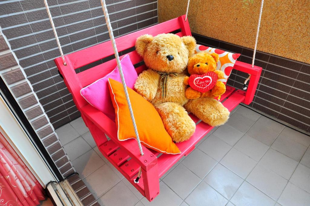 two teddy bears sitting on a swing at Happy Orange Homestay in Dongshan