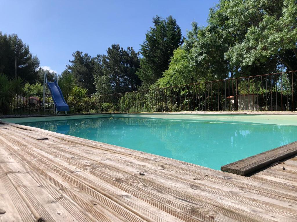 une piscine avec une terrasse en bois et un toboggan dans l'établissement Royantine, à Aubagne