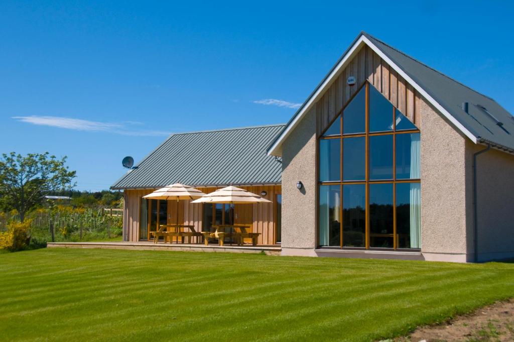 a large house with a grass yard at Clovenstone Lodges in Inverurie