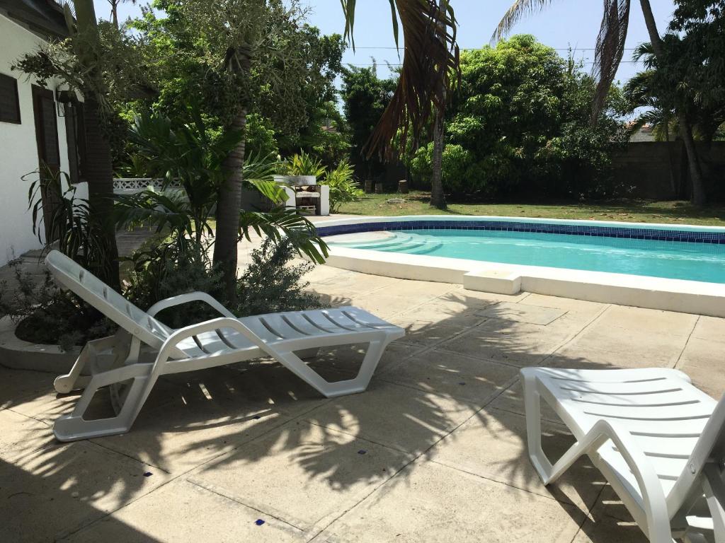 two lounge chairs and a swimming pool in front of a house at Reef Winds Villa in Runaway Bay