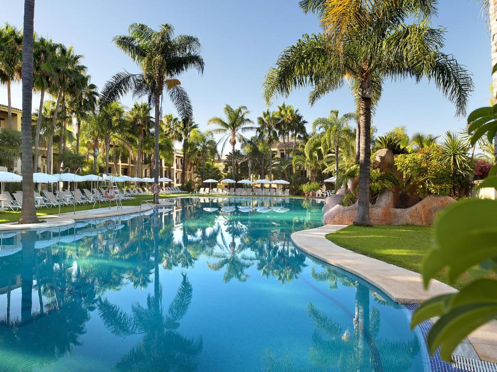 a pool at a resort with palm trees at BlueBay Banús in Marbella