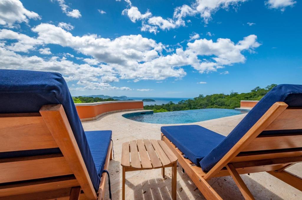 un patio con 2 sedie e una piscina di Ocean-View Villa Above Potrero Overlooking Two Bays a Guanacaste