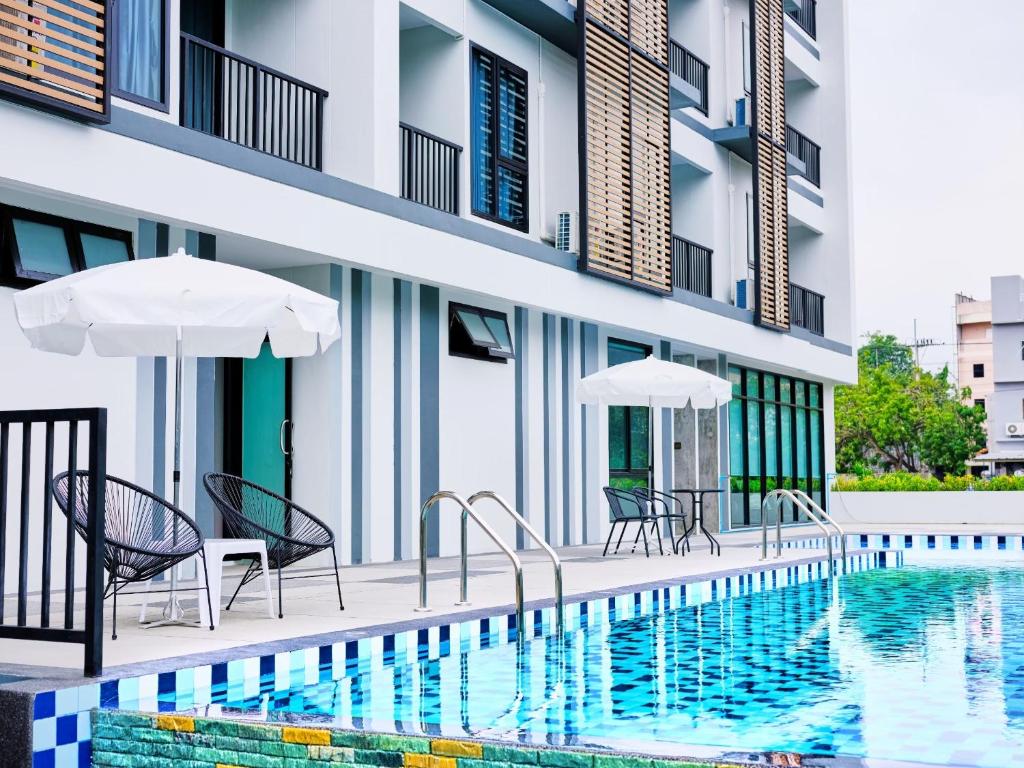 a swimming pool with chairs and umbrellas next to a building at Baan Pakdi Pattaya in Pattaya Central