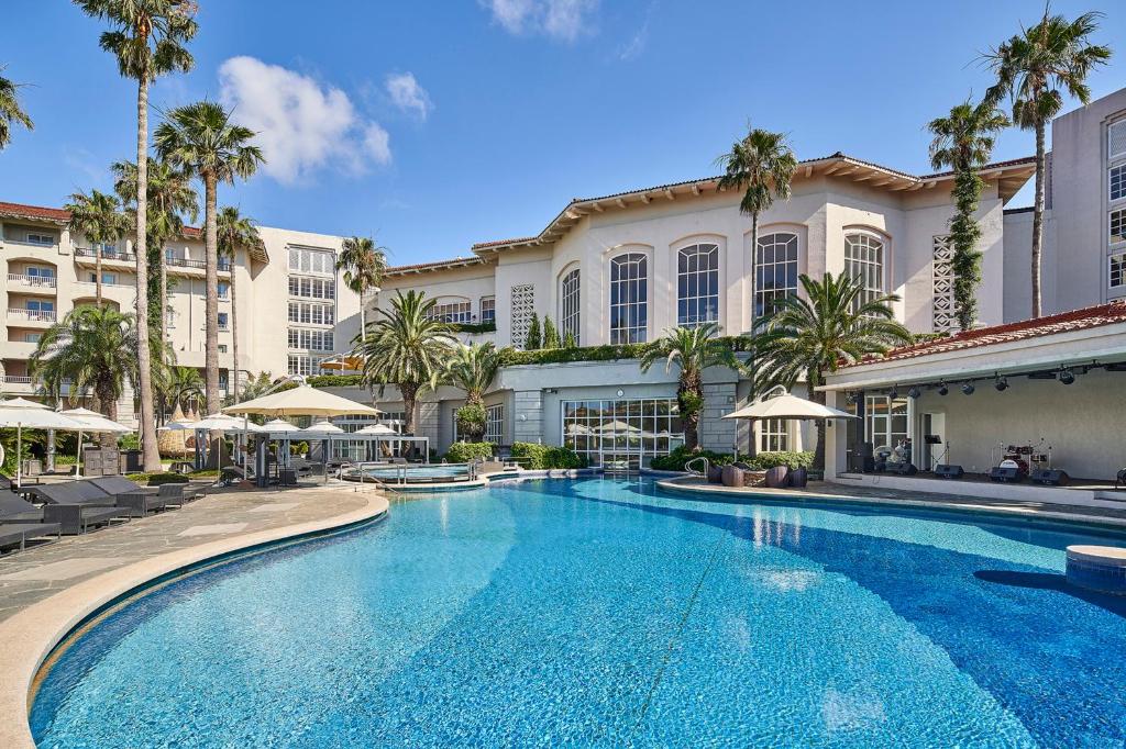 a swimming pool with palm trees in front of a building at The Shilla Jeju in Seogwipo