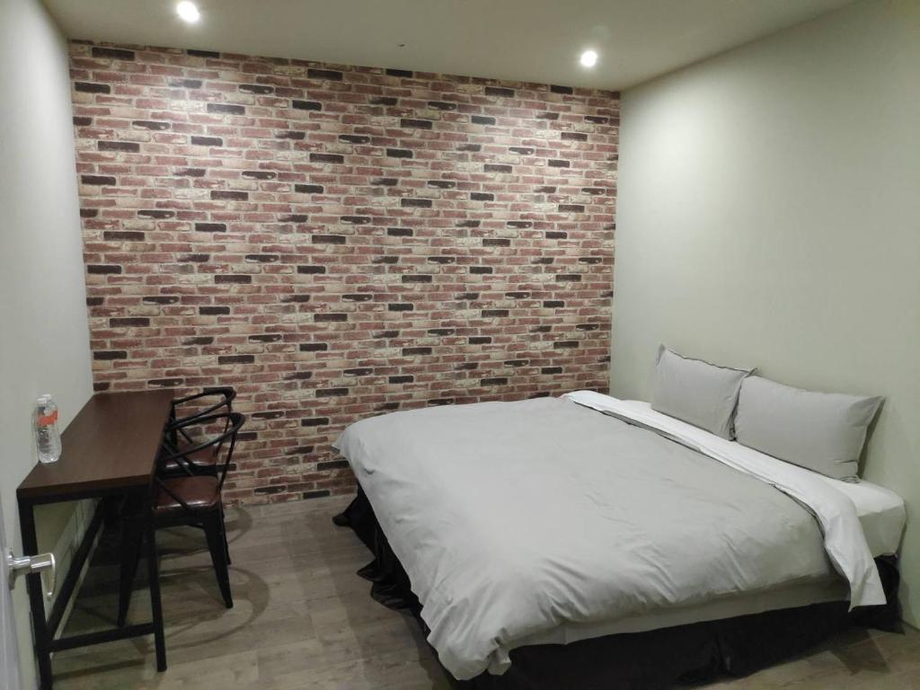 a bedroom with a bed and a brick wall at Saint Hostel in Beigang