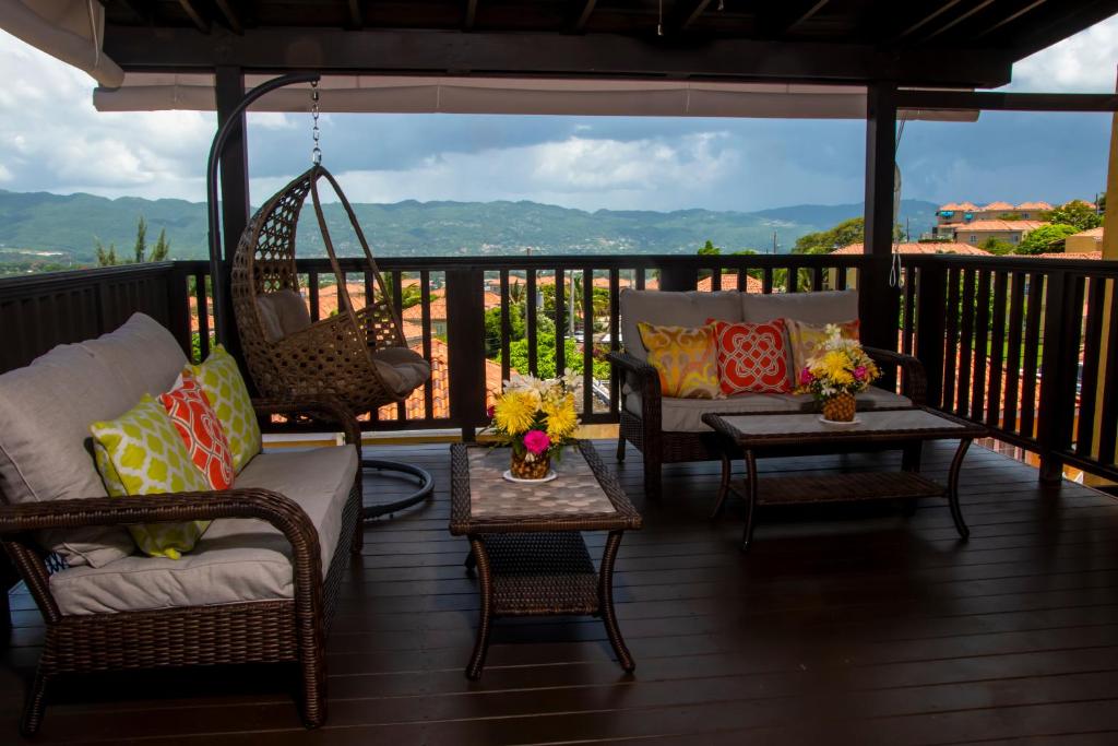eine Veranda mit Stühlen, Tischen und einer Schaukel in der Unterkunft Vacation Getaway in Mango Walk Country Club in Montego Bay