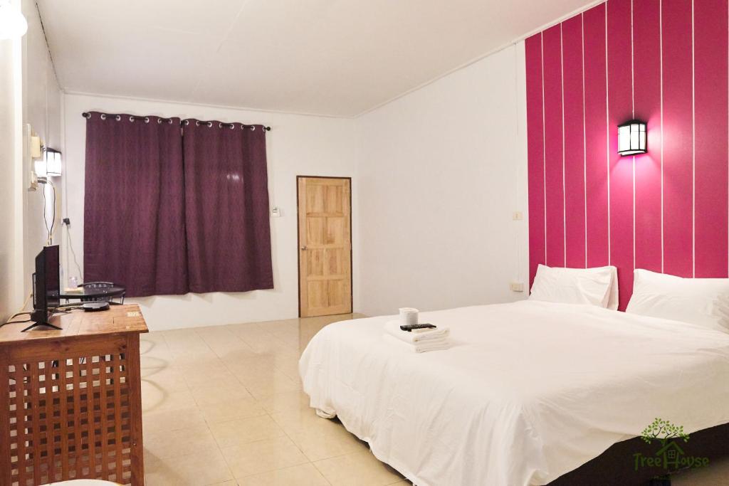 een slaapkamer met een groot wit bed en paarse muren bij Tree House Resort Betong in Betong