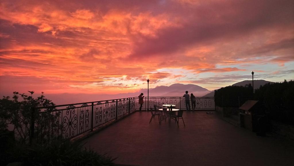 two people standing on a balcony with a sunset at Star Villa in Ren&#39;ai