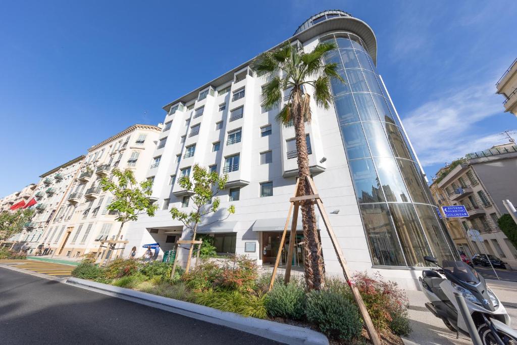 un edificio con una palmera delante de él en Goldstar Apartments & Suites, en Niza