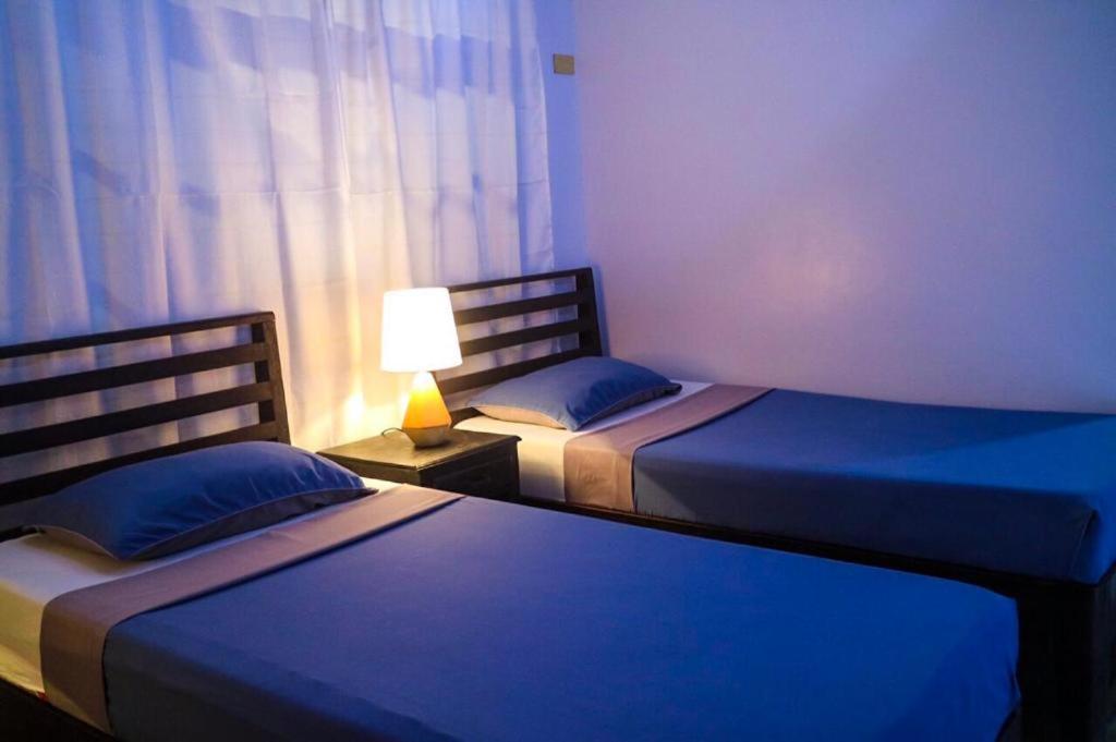 a bedroom with two beds and a lamp on a table at Hostel Privado in Puerto Princesa City