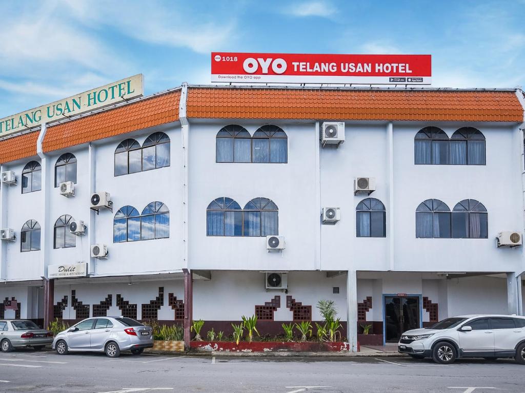 a white building with cars parked in front of it at Super OYO 1018 Telang Usan Hotel Miri in Miri