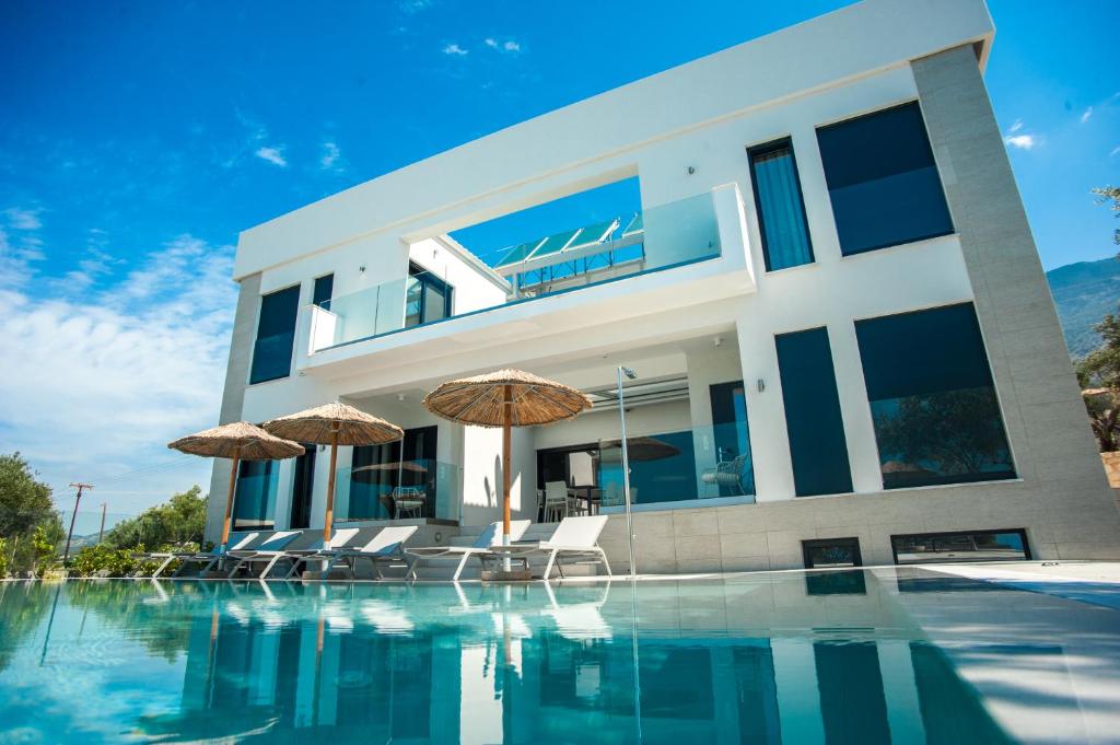 a house with a swimming pool with chairs and umbrellas at Premium Ionian Villas - Vlachata in Vlachata