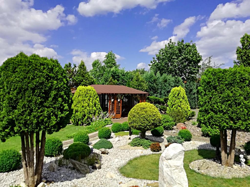 a garden with trees and a building in the background at Hotel Hawana in Bydgoszcz