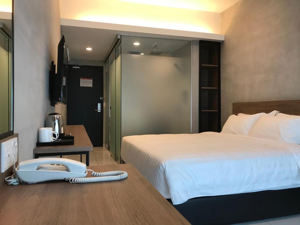 a hotel room with a bed and a phone on a desk at Dandelion Inn in Simpang Pulai