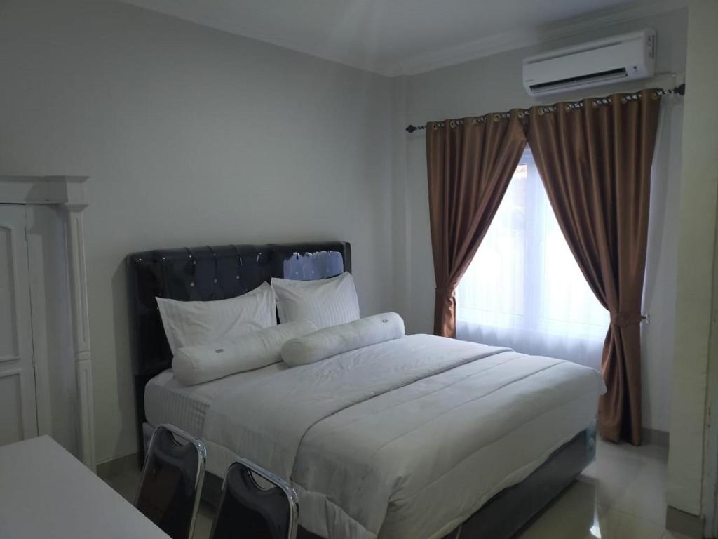 a bedroom with a bed with pillows and a window at RedDoorz near Palembang Airport 2 in Palembang