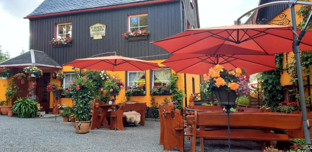 um restaurante com mesas e guarda-sóis em frente a um edifício em Haus Tadeus em Kurort Altenberg