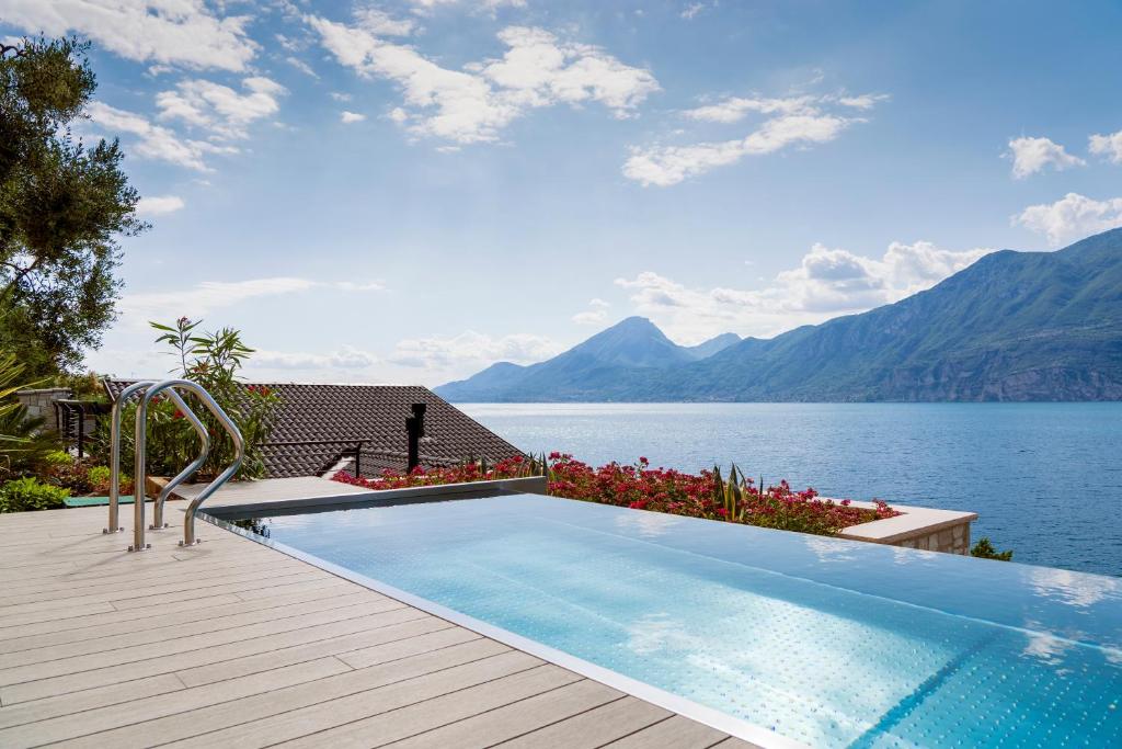 a swimming pool with a view of the water and mountains at Sunset Residence in Brenzone sul Garda