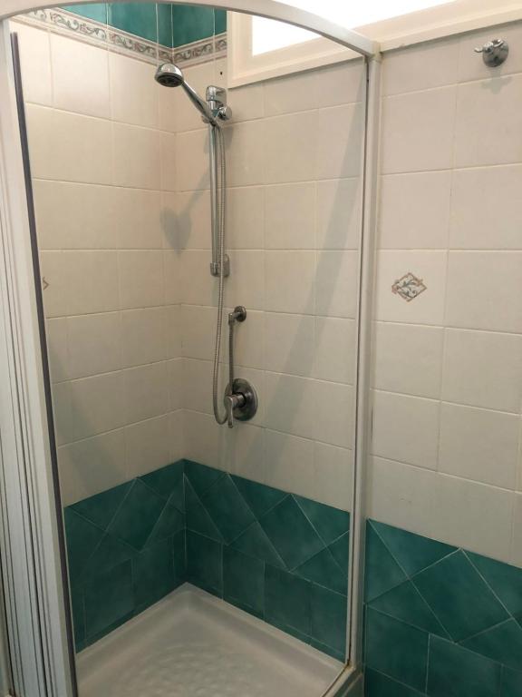 a shower with a glass door and green and white tiles at La Casa Sulla Scogliera in Cefalù