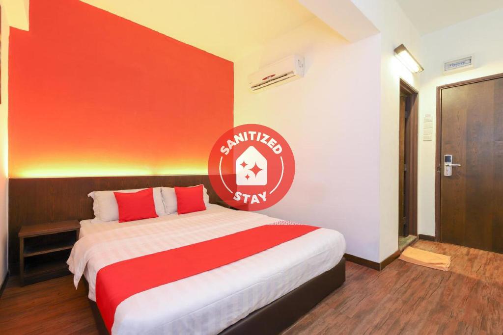 Cette chambre comprend un grand lit avec des draps rouges et blancs. dans l'établissement OYO 724 Hotel Madras, à Kuala Lumpur