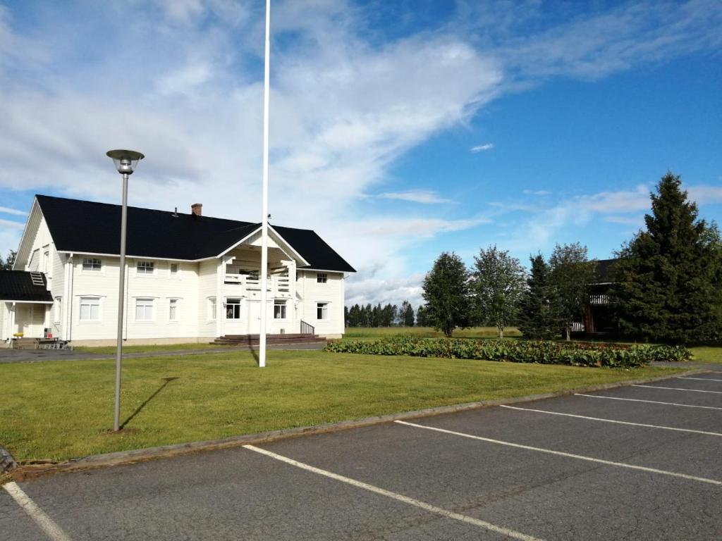 um grande edifício branco com um mastro de bandeira num parque de estacionamento em Hannuksen Piilopirtti em Tyrnävä