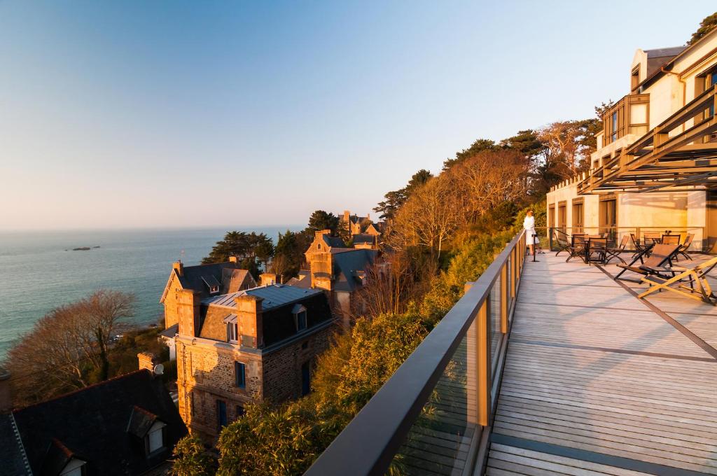 a woman standing on a balcony looking at the ocean at L'Agapa Hôtel - Spa Codage in Perros-Guirec