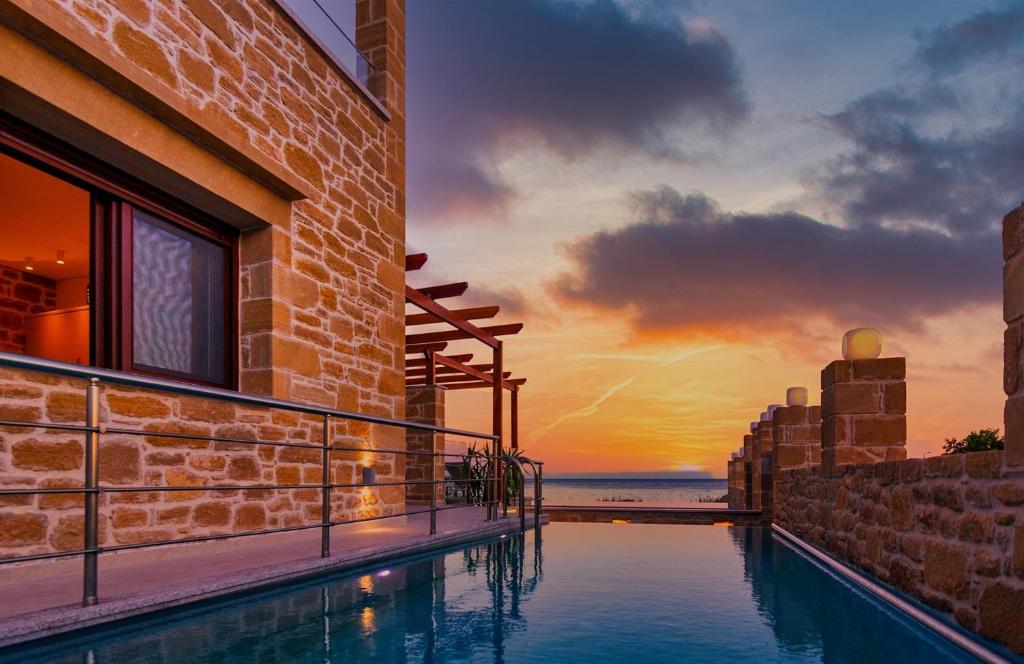 - une piscine sur le côté d'un bâtiment avec un coucher de soleil dans l'établissement Anma Villa, à Paleóchora