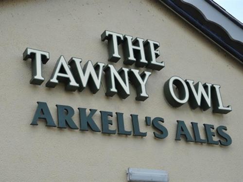 un cartello sul lato di un edificio di The Tawny Owl a Swindon