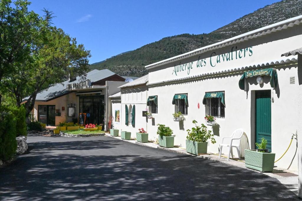 a white building with plants in a street at Hotel Grand Canyon du Verdon in Aiguines