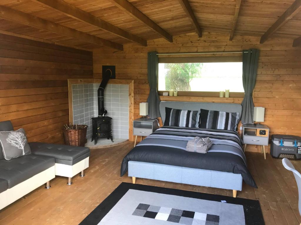 1 dormitorio con cama, sofá y chimenea en Old Mill House Log Cabins, en Dorchester