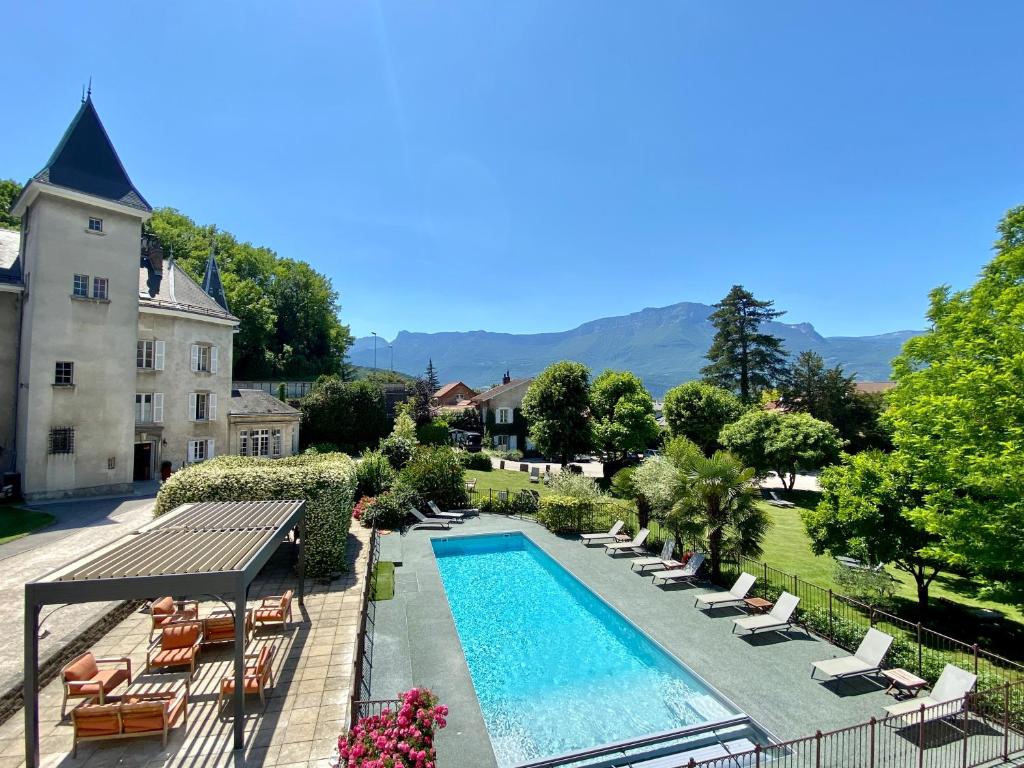 an outdoor swimming pool with lounge chairs and a building at Château & Spa De La Commanderie in Eybens