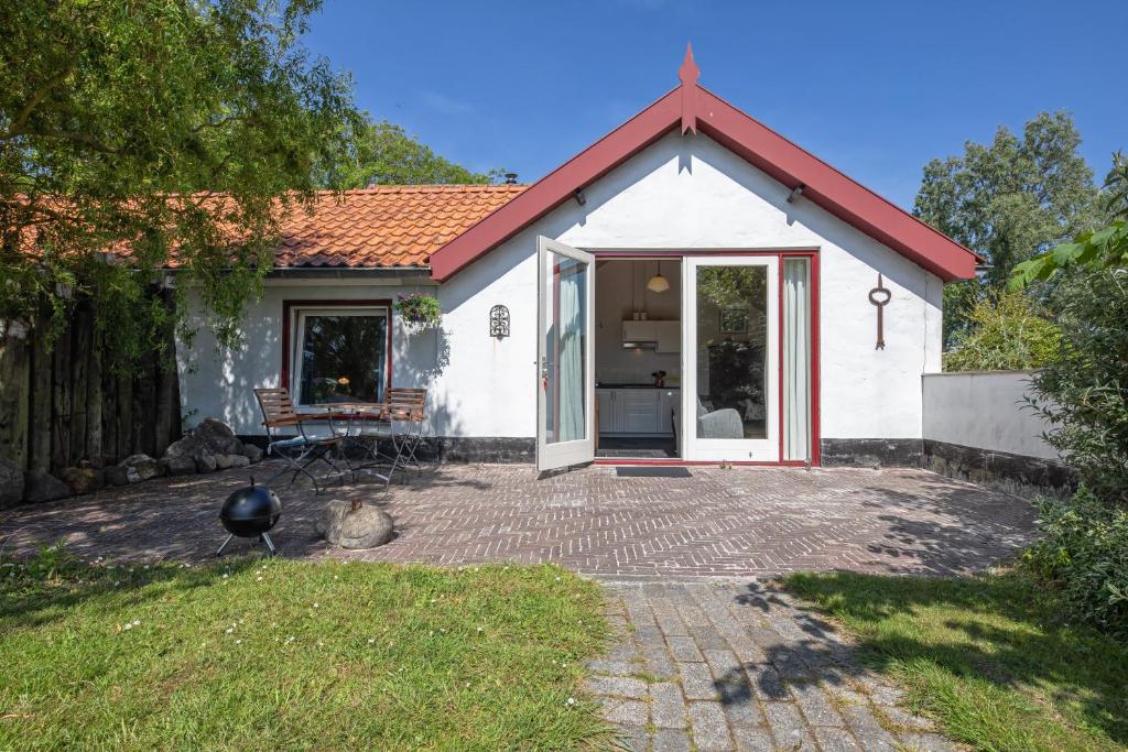 una pequeña casa blanca con techo rojo en De Vrijheid-Plantage, en De Cocksdorp