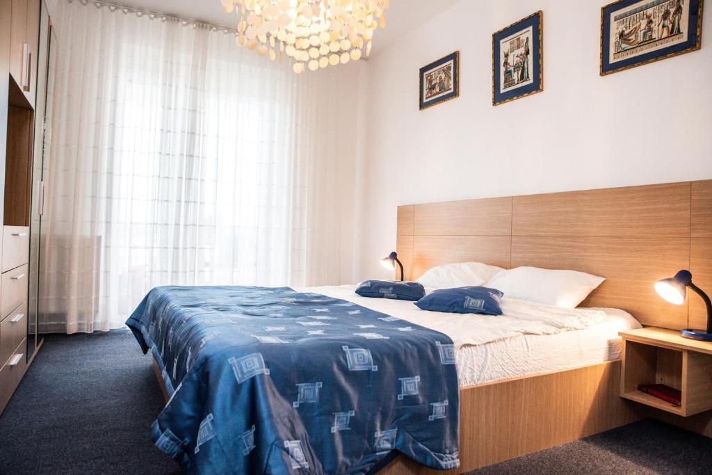 a bedroom with a large bed with a blue blanket at Club Onix Apartments in Neptun