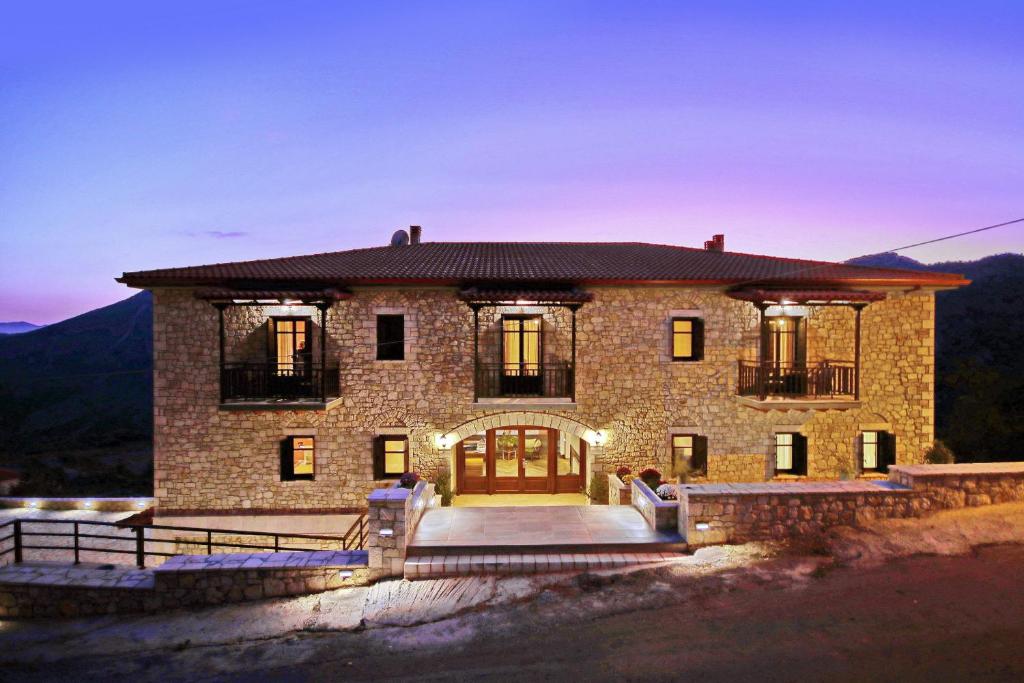 une grande maison en pierre avec des personnes assises sur les marches. dans l'établissement ΜΠΑΡΟΥΤΟΜΥΛΟΣ -Baroutomilos, à Dimitsana