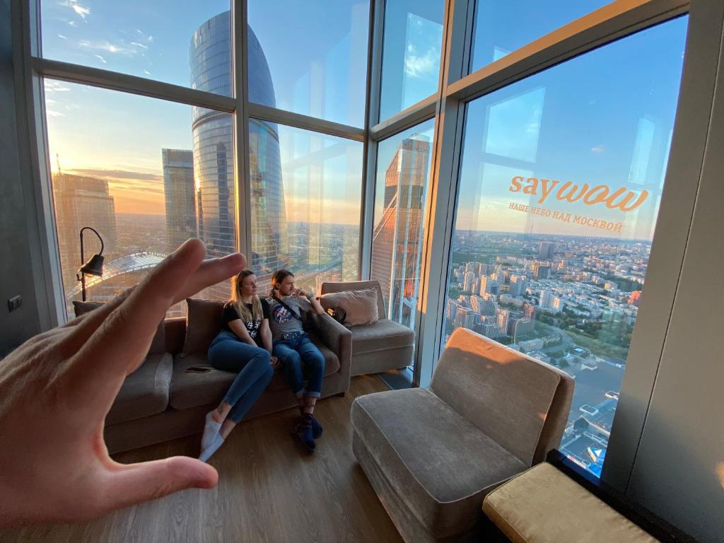 モスクワにあるСамый высокий отель в Европе с лучшим видом на Москву - Say Wow Capsule Hotelの手を繋ぎ、カップルが建物のソファに座っている