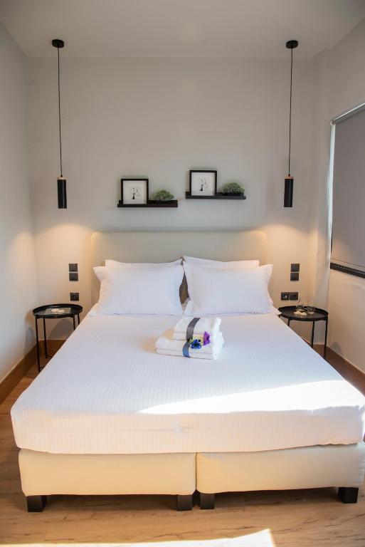 a white bed in a bedroom with two pictures on the wall at Urban Sea View Lofts #2 in Chalkida