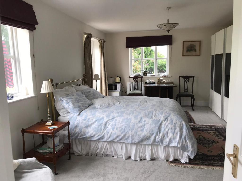 1 dormitorio con cama, mesa y ventanas en The Gardens en Daventry