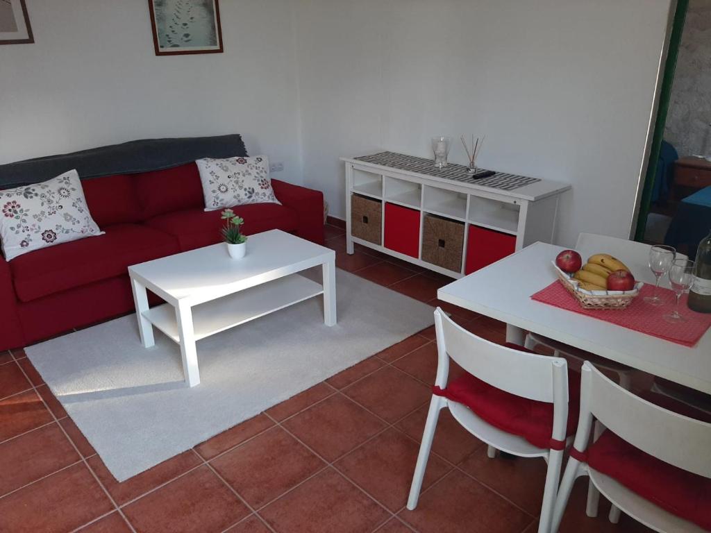 a living room with a red couch and a table at Apartamento CHINIJO in Caleta de Sebo