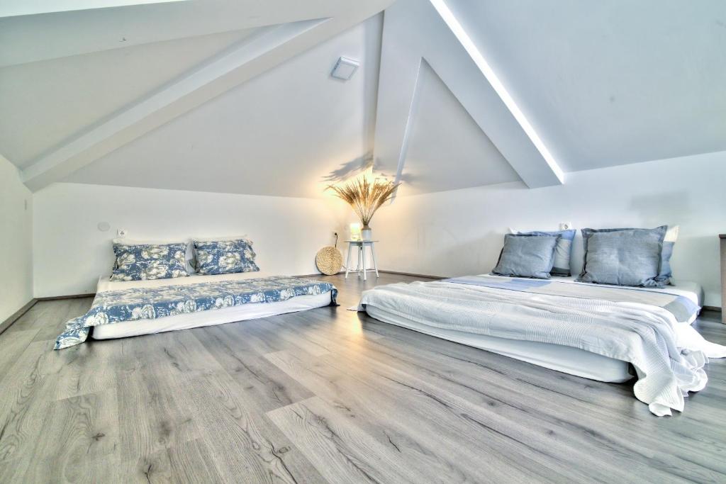 two beds in a white room with wooden floors at Dida moj in Senj