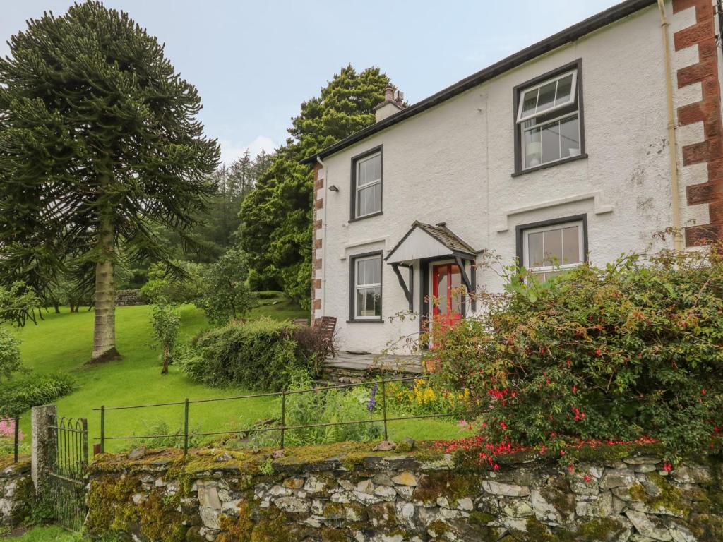 a white house with a stone wall and a yard at High Torver House in Coniston