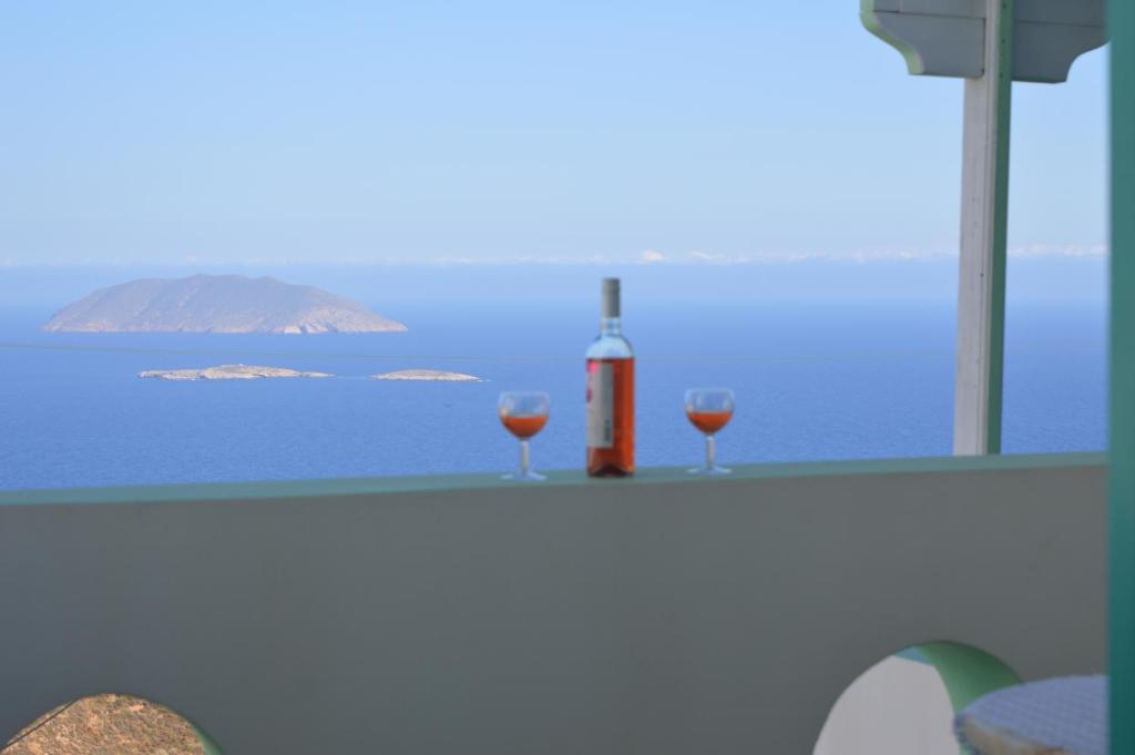 two glasses of wine sitting on a table near the ocean at Villa Galini in Anafi