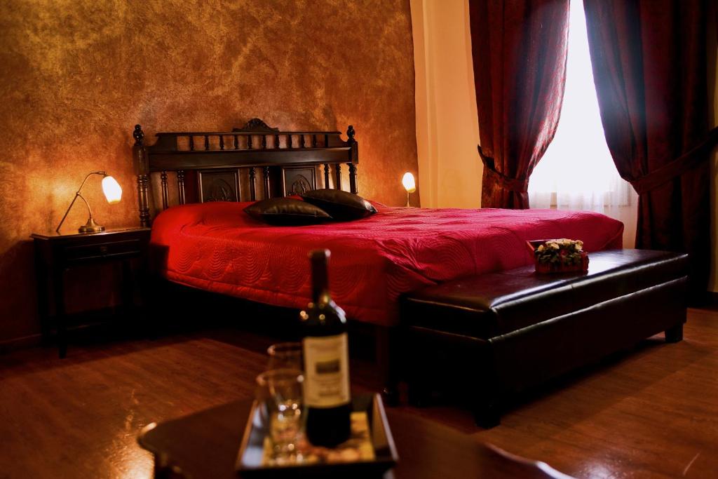 1 dormitorio con 1 cama roja y 1 botella de vino en Andromeda Suites, en Nauplia