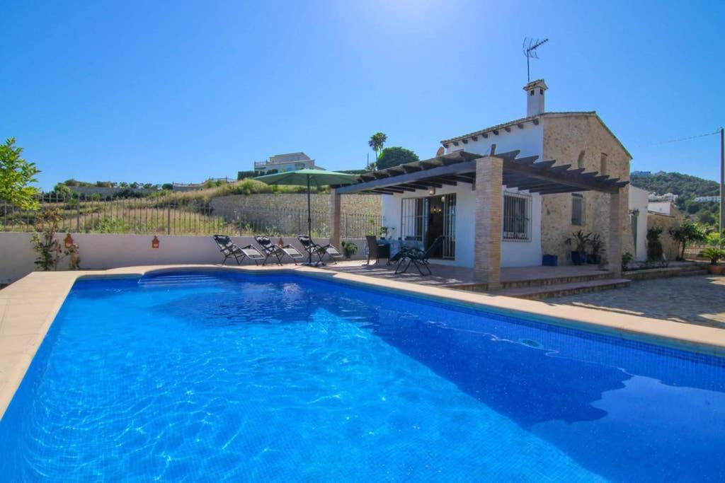 une piscine bleue en face d'une maison dans l'établissement Chalet con piscina privada en Calpe - Terrasala, à Casas de Torrat