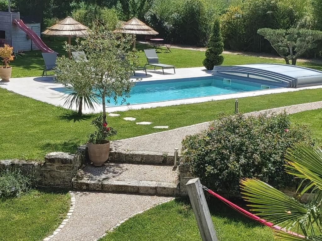 a swimming pool in a yard with a garden sidx sidx sidx at Chambres d'hôtes Les Marguerites in Champdolent
