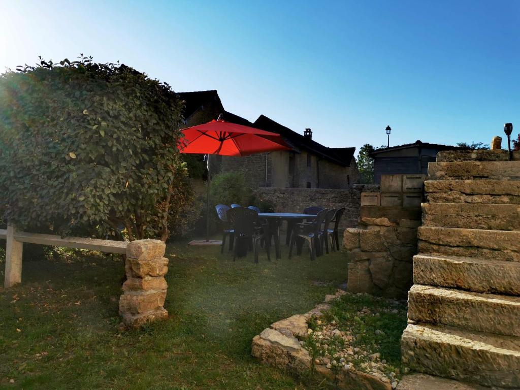 a patio with a table with a red umbrella at Gîte des 3 vallées in Baume-les-Messieurs