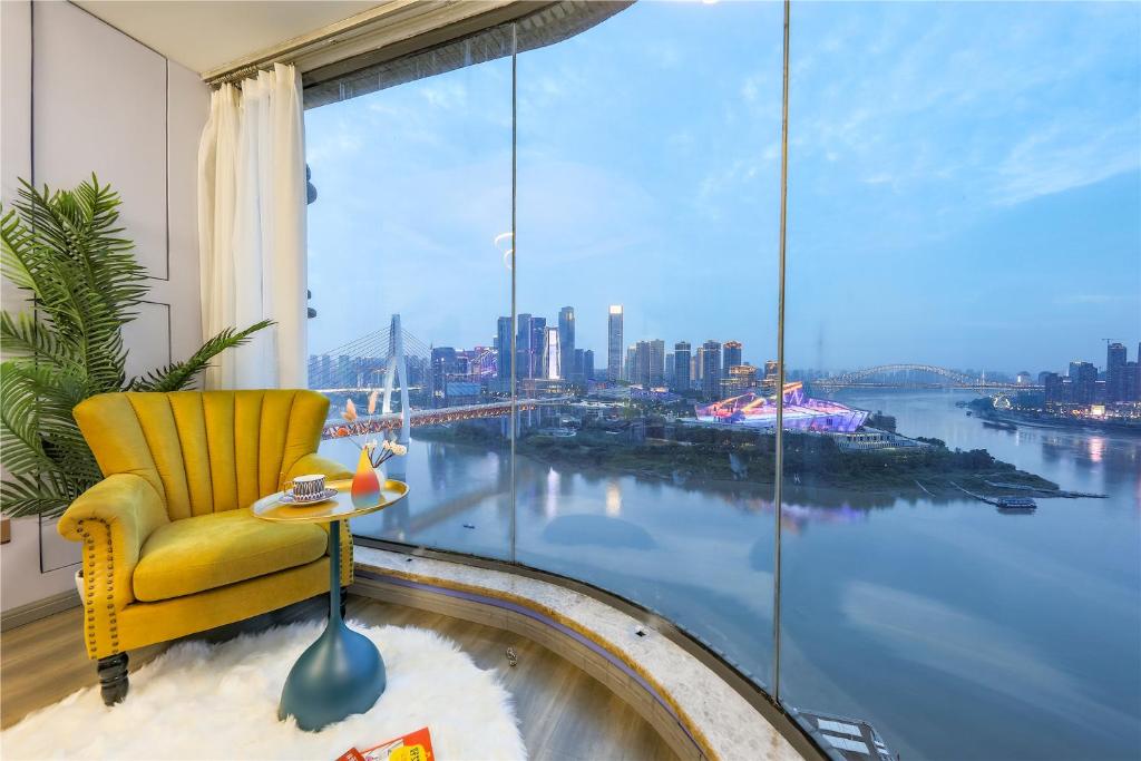 a yellow chair in a room with a large window at Baihong.Riverview Apartment in Chongqing