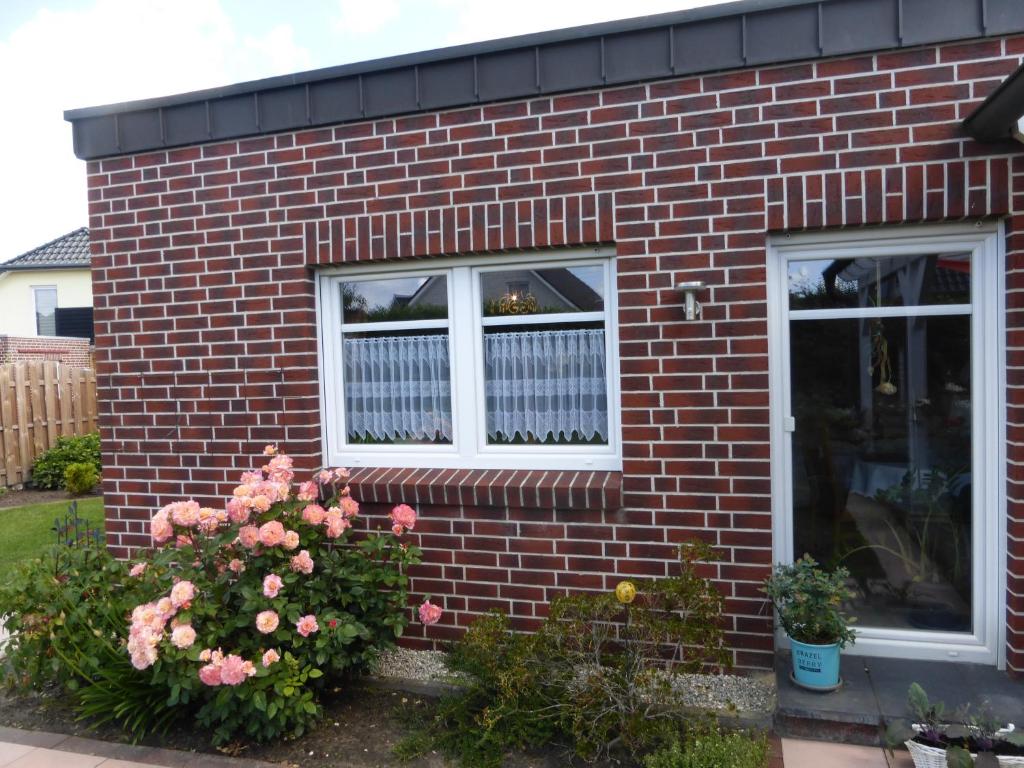 een rood bakstenen huis met twee ramen en bloemen bij Appartment am Fingerhut in Cloppenburg