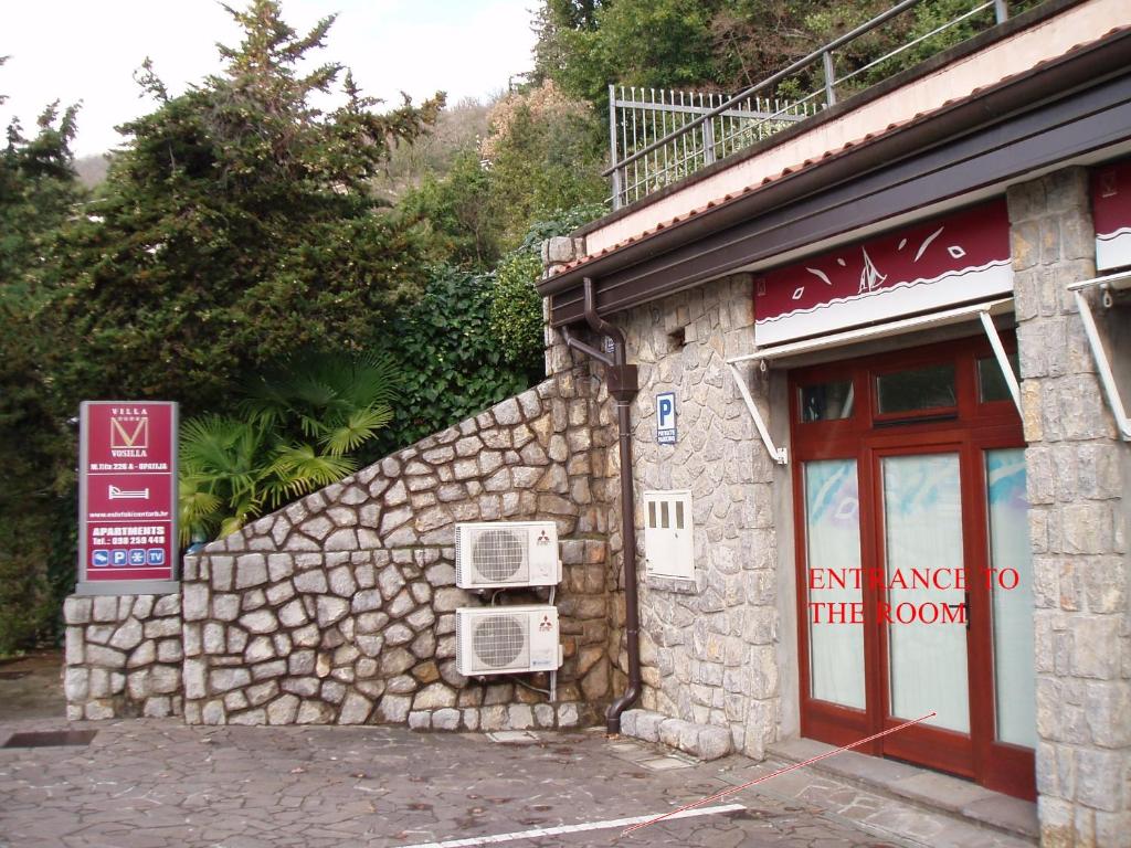 a stone building with a red door and a window at Soba Bosa in Opatija