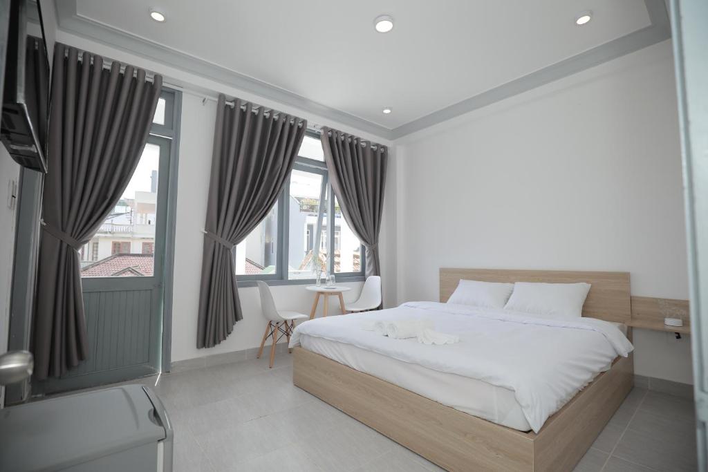 Schlafzimmer mit einem großen Bett und Fenstern in der Unterkunft M Hotel Đà Lạt in Da Lat