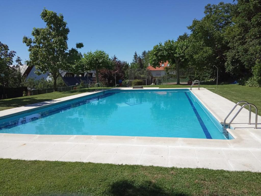 a large swimming pool in a yard with grass at La Casita de la Sierra Cercedilla in Cercedilla