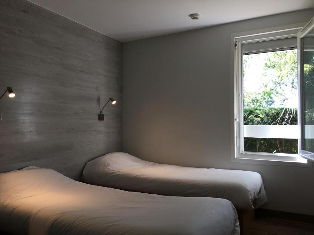 2 Betten in einem Zimmer mit Fenster in der Unterkunft Fast Hotel Colmar Houssen in Houssen